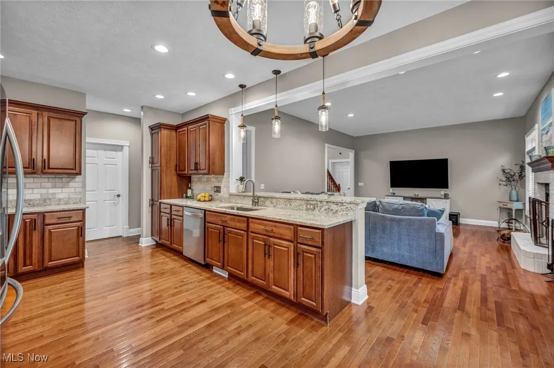 Kitchen with stainless steel dishwasher, light wood-style floors, brown cabinets, and recessed lighting
