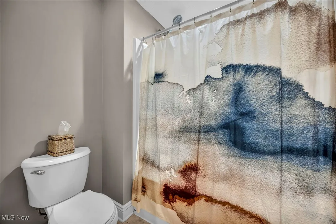 Bathroom featuring toilet and a shower with shower curtain
