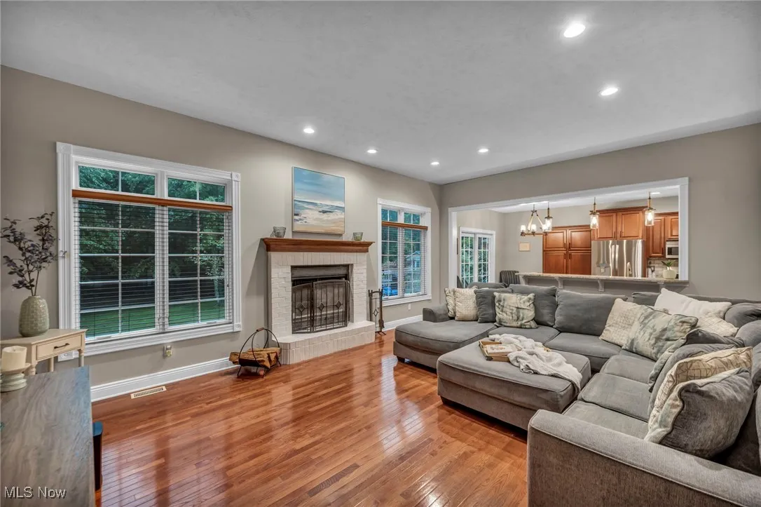 Living area featuring light wood finished floors, recessed lighting, a chandelier, plenty of natural light, and a fireplace
