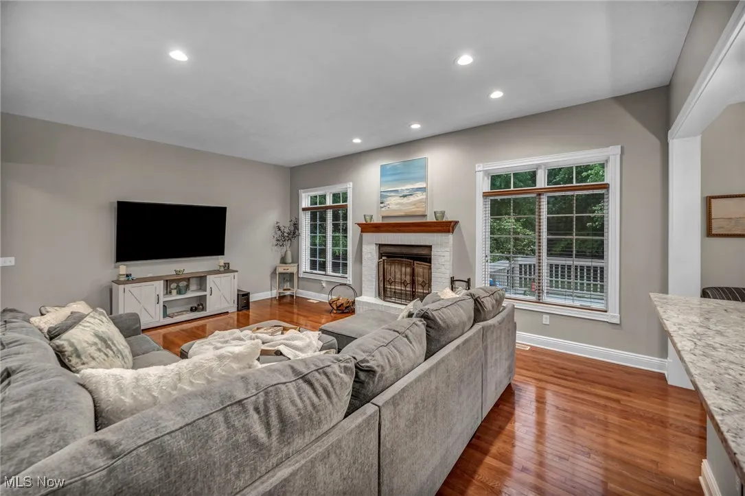 Living area with recessed lighting, plenty of natural light, wood finished floors, and a fireplace with raised hearth