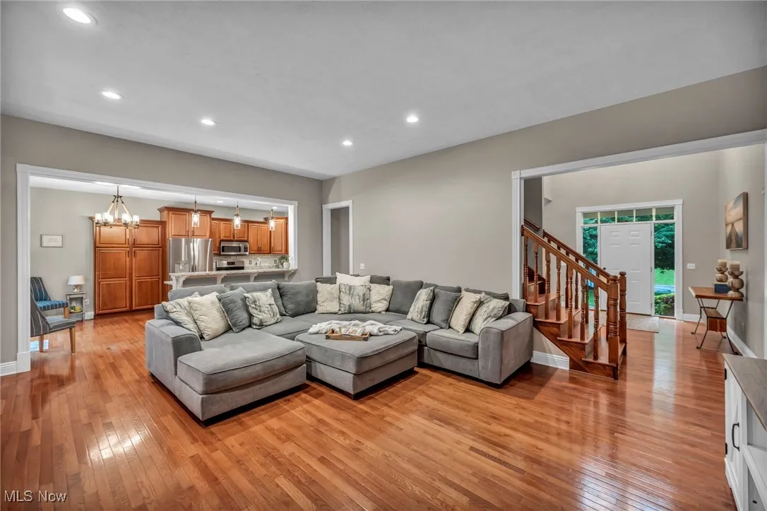 Living area with light wood-type flooring, stairs, recessed lighting, and a chandelier