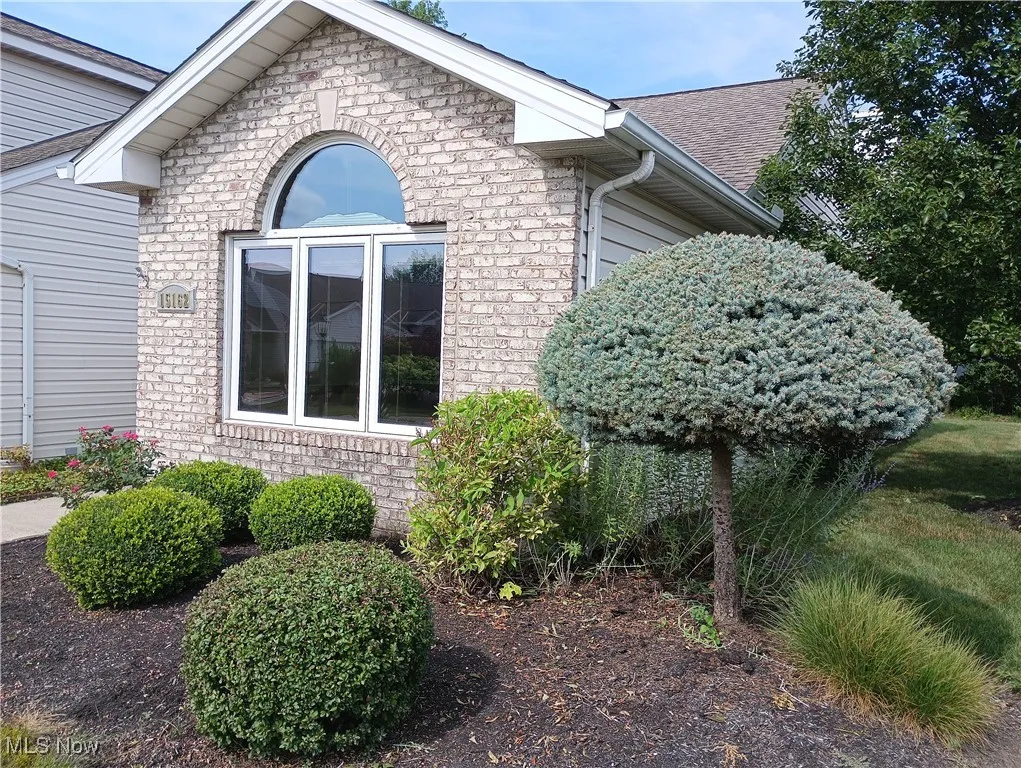 View of side of home featuring a shingled roof and brick siding