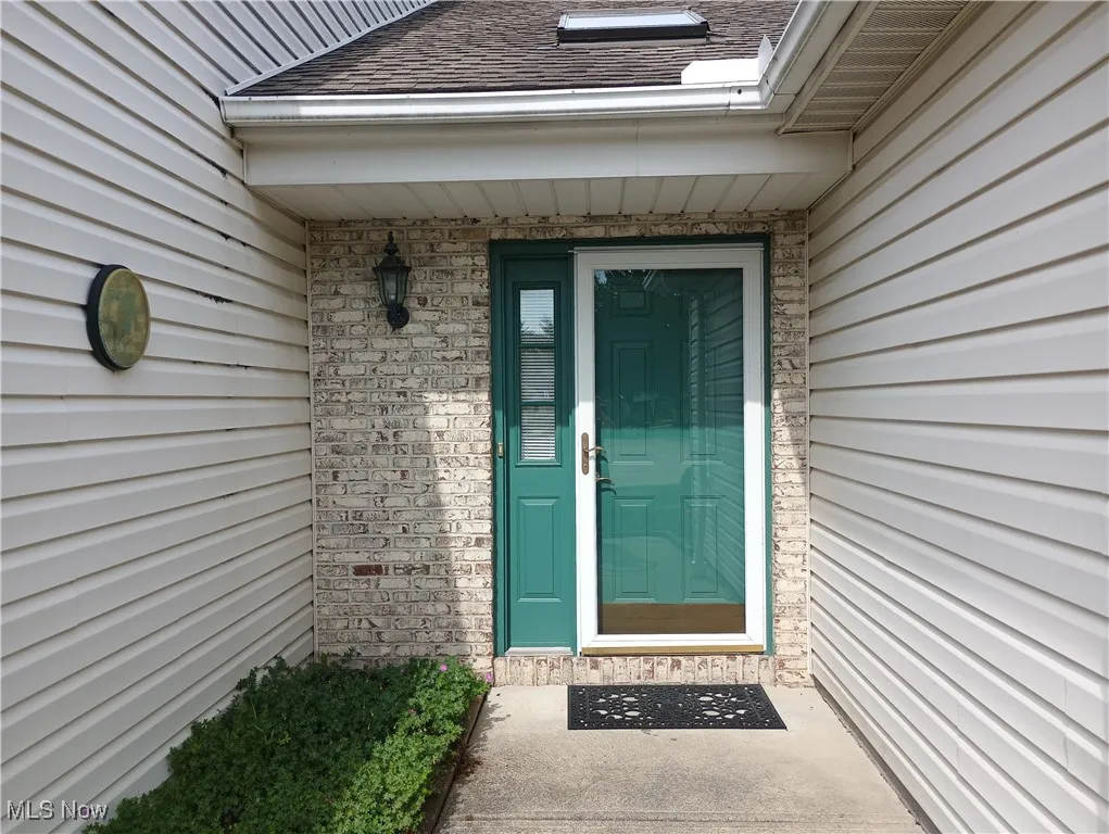 Property entrance featuring brick siding and a shingled roof