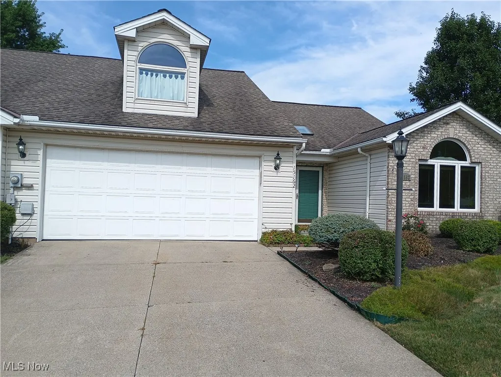 View of front of house with a shingled roof, concrete driveway, and a garage