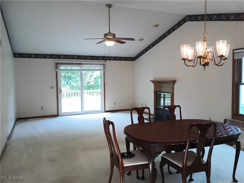 Dining room with lofted ceiling, carpet flooring, ceiling fan, and a chandelier