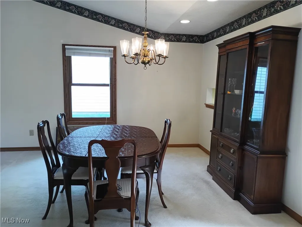 Dining area featuring light carpet and a chandelier