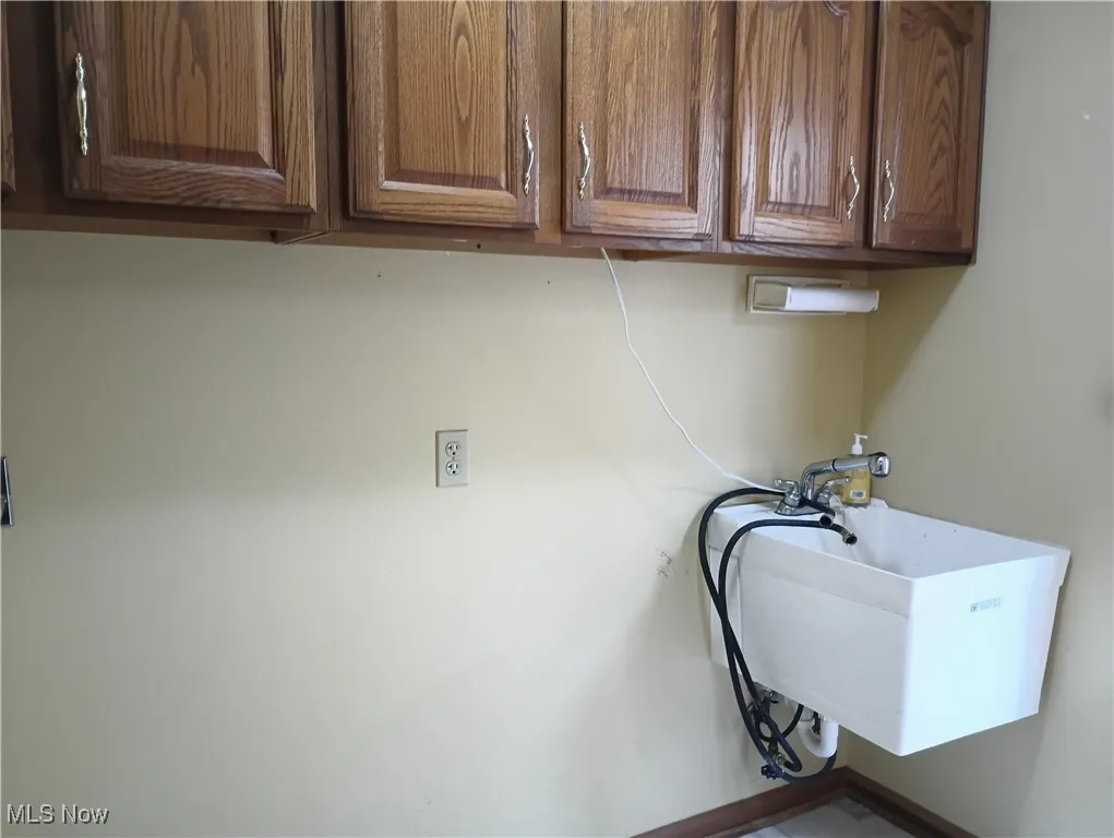 Laundry room with cabinet space and baseboards