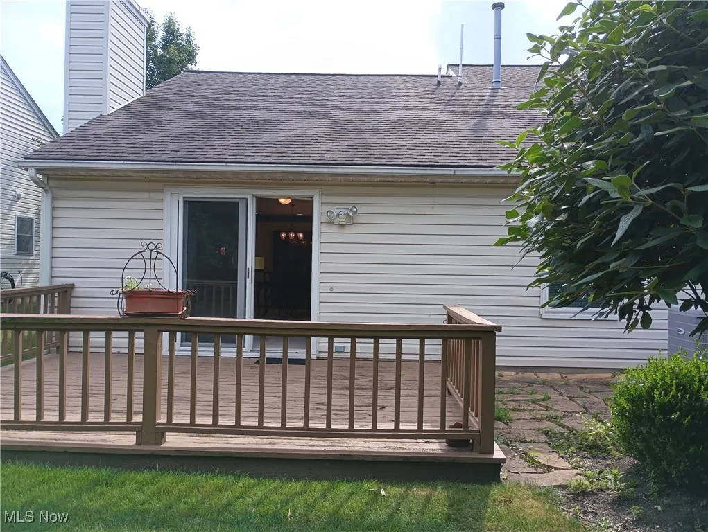 Back of property featuring a shingled roof, a wooden deck, and a chimney