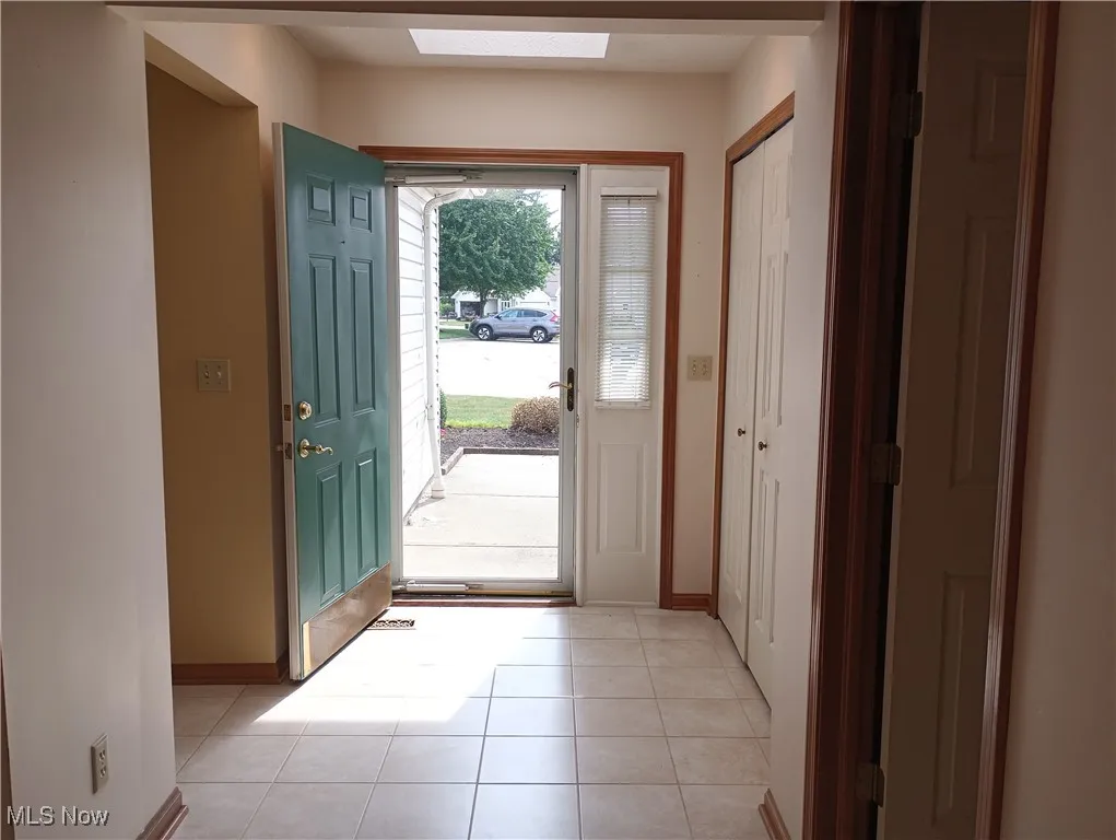 Doorway to outside featuring light tile patterned floors and a skylight
