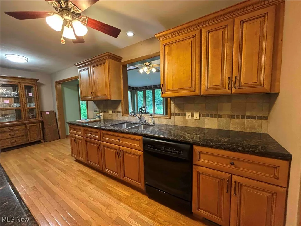 Kitchen with brown cabinets, decorative backsplash, dishwasher, ceiling fan, and light wood-style floors