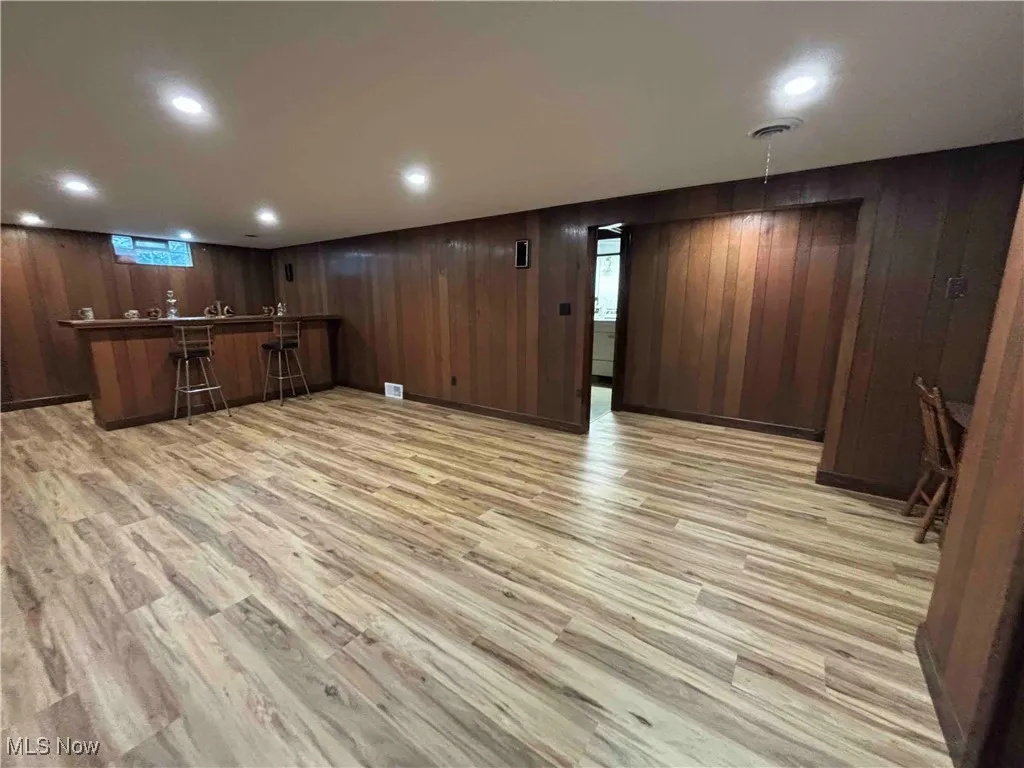 Indoor bar featuring wooden walls, light wood finished floors, and recessed lighting