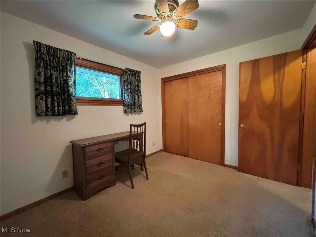 Home office with light carpet and ceiling fan