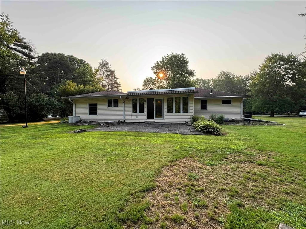 Back of property at dusk featuring a patio and a yard