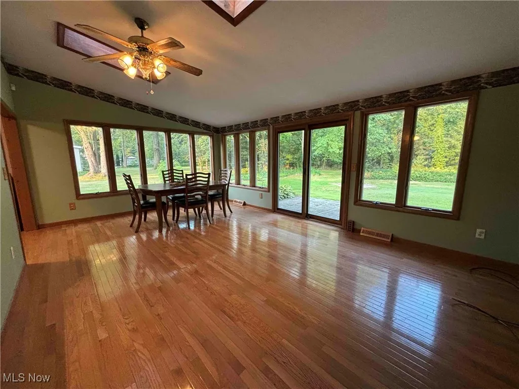 Sunroom / solarium featuring hardwood / wood-style floors, a skylight, and lofted ceiling