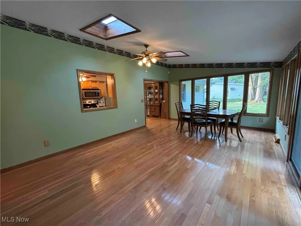 Dining room featuring light wood finished floors, a skylight, and ceiling fan