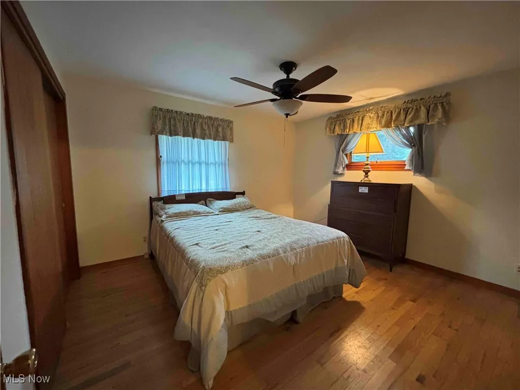 Bedroom featuring light wood-style floors, multiple windows, and ceiling fan