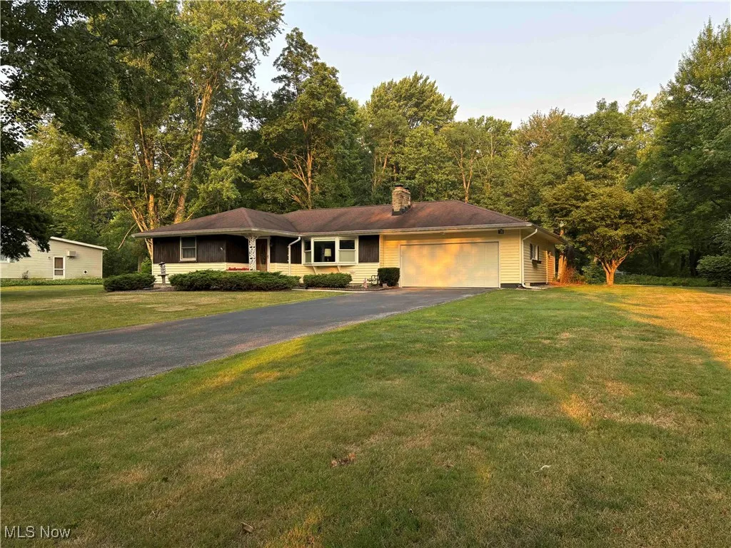 Single story home with driveway, a chimney, a garage, and a front yard