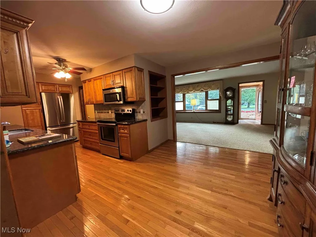 Kitchen featuring appliances with stainless steel finishes, dark countertops, open floor plan, and light wood finished floors