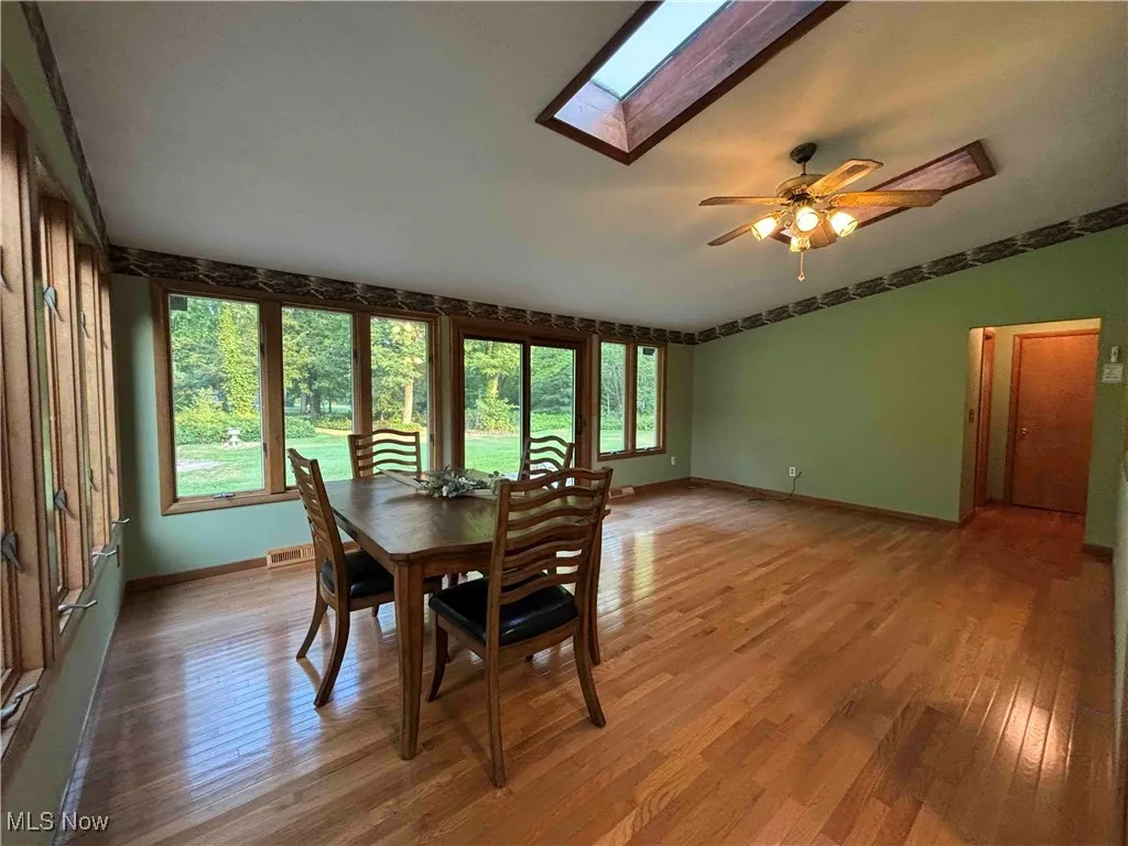 Dining area featuring a skylight, light wood-style floors, and ceiling fan