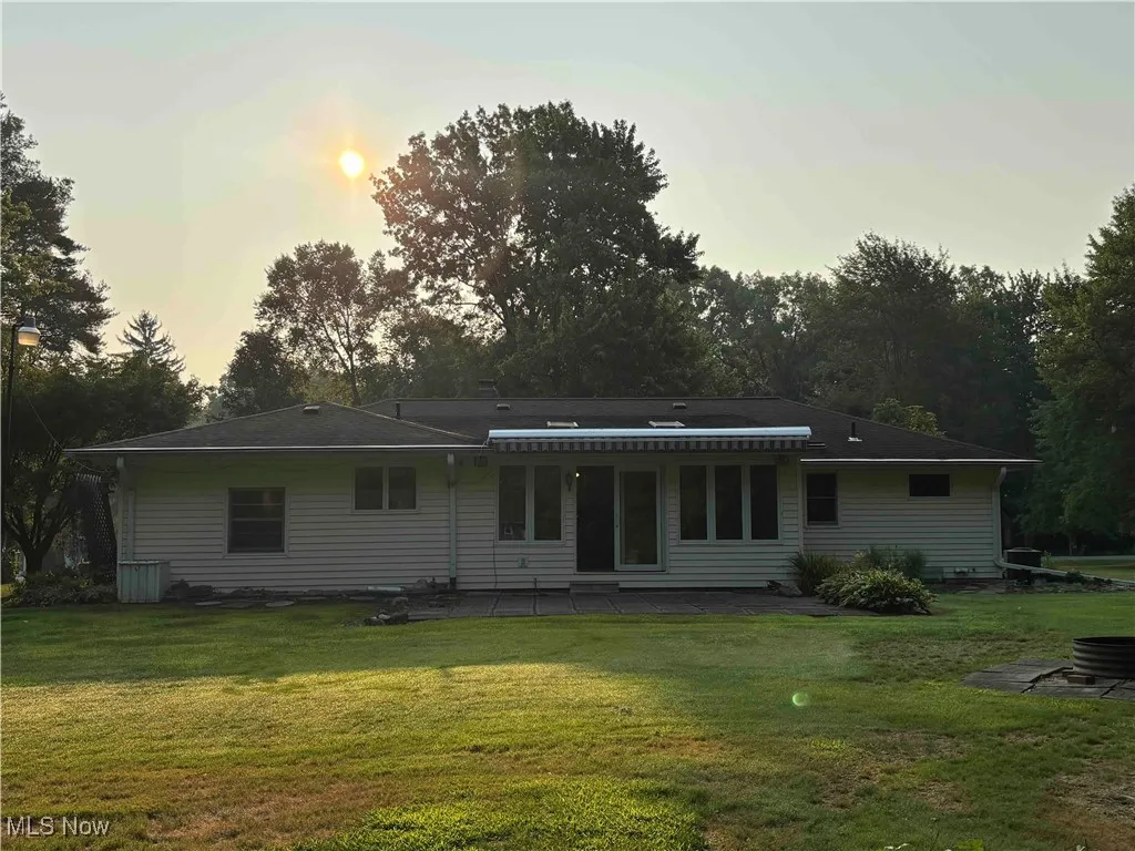 Back of property at dusk featuring a yard and a patio