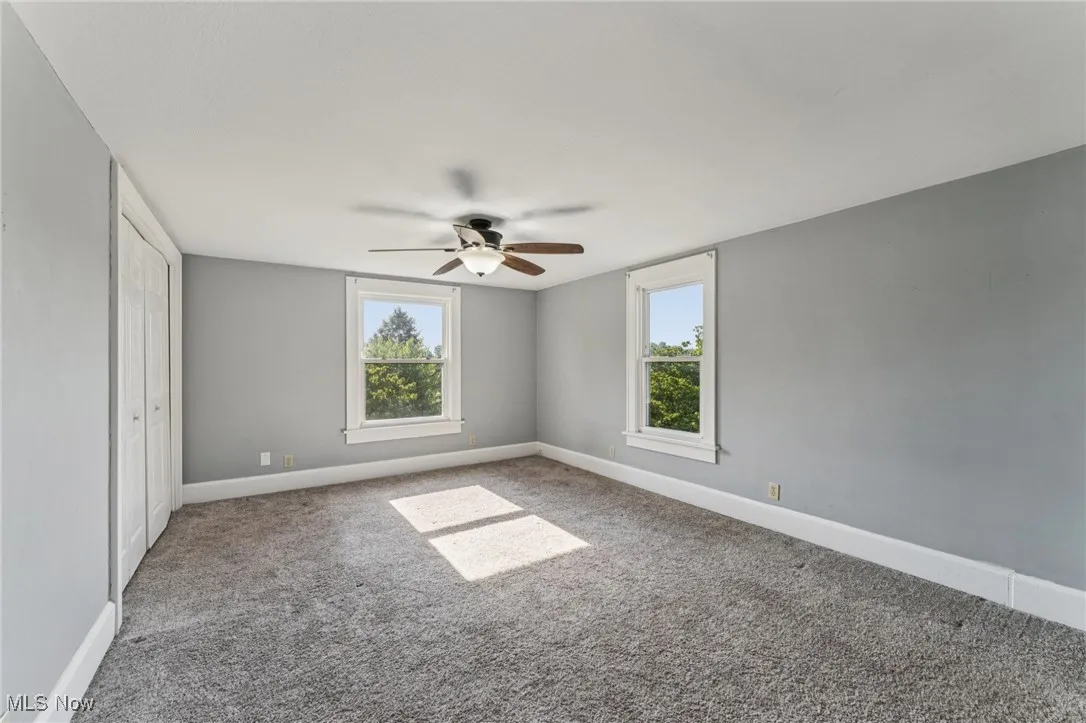 Unfurnished bedroom featuring carpet, multiple windows, and ceiling fan