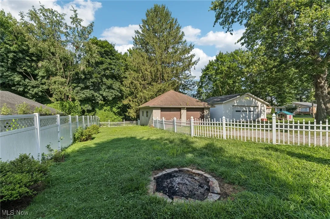 Fenced backyard featuring a fire pit and a detached garage