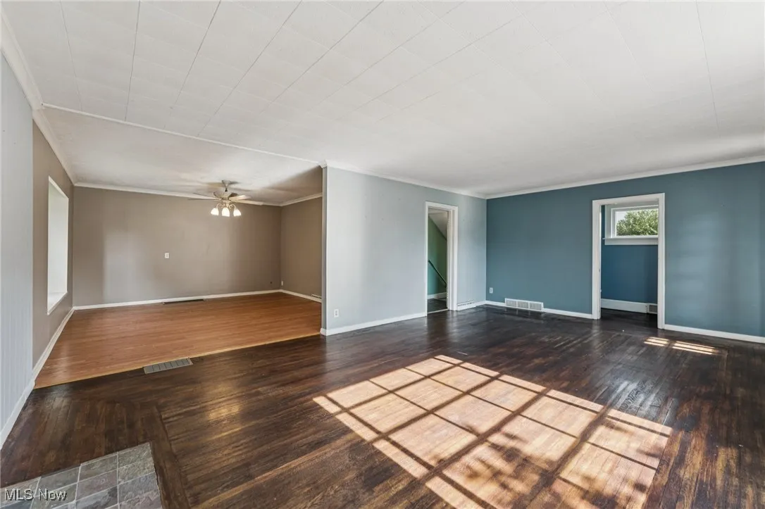 Spare room featuring wood finished floors, crown molding, and ceiling fan
