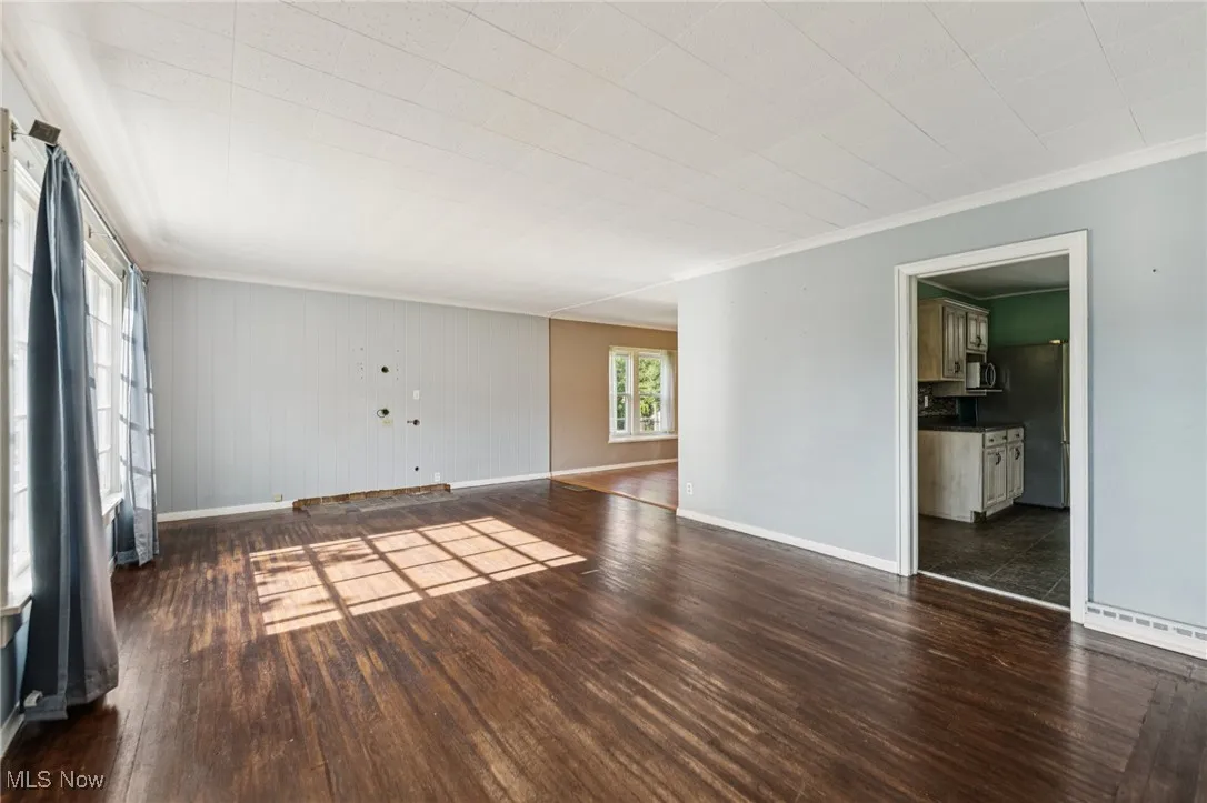 Empty room with ornamental molding and dark wood finished floors