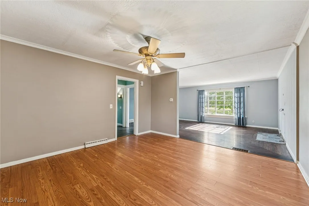 Spare room featuring crown molding, wood finished floors, a textured ceiling, and ceiling fan