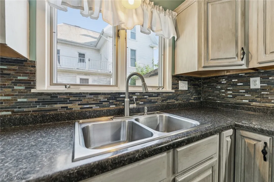 Kitchen featuring tasteful backsplash, dark countertops, and light brown cabinetry