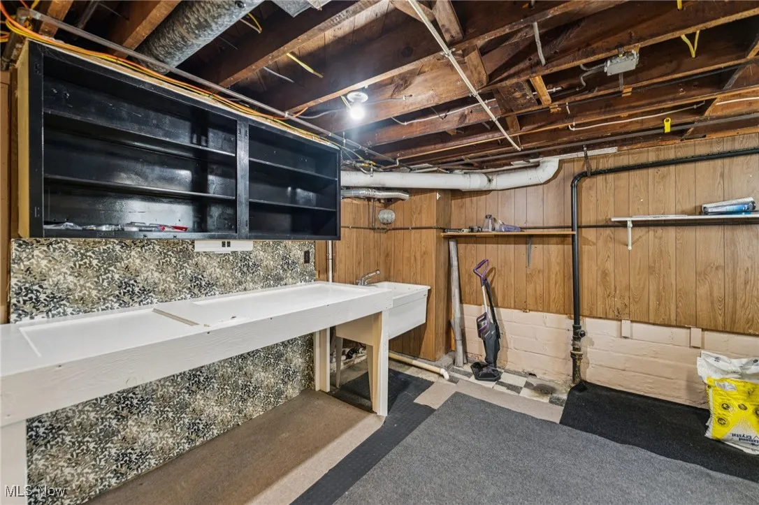 Unfinished basement with wood walls and a sink