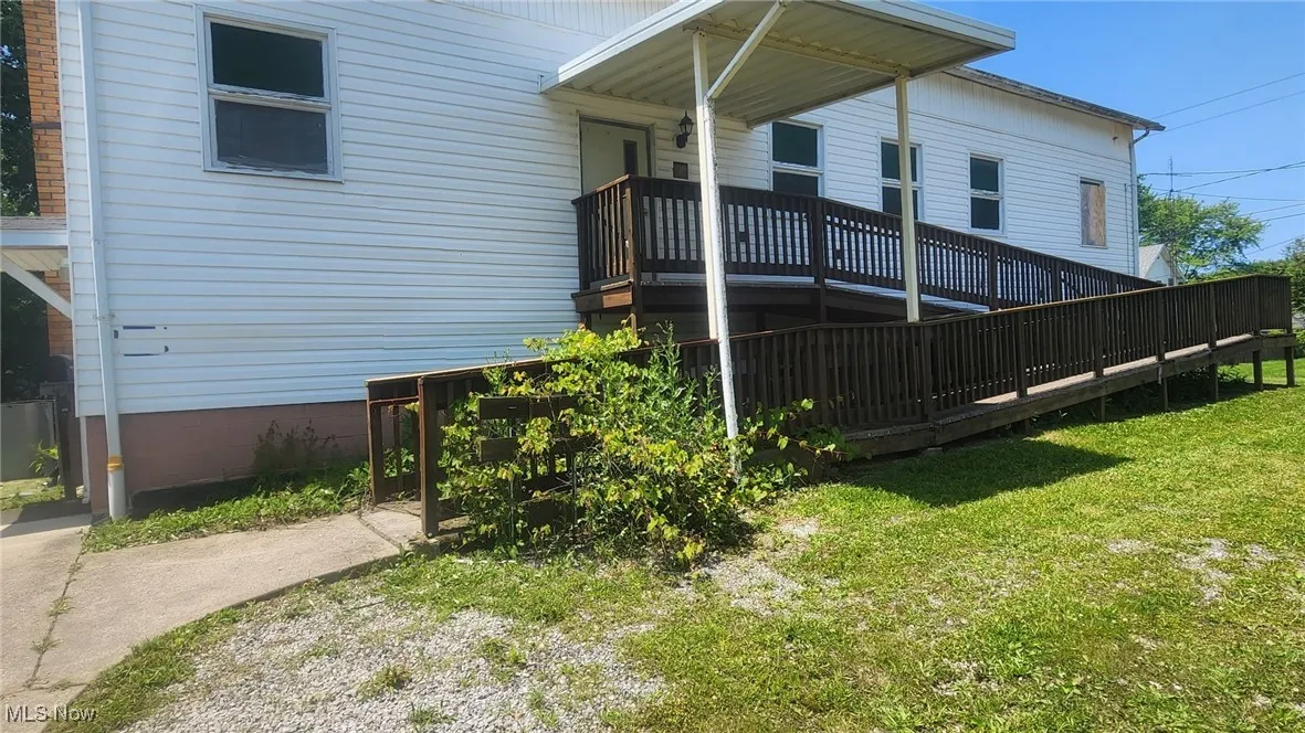 View of home's exterior featuring a lawn and a wooden deck with a ramp.