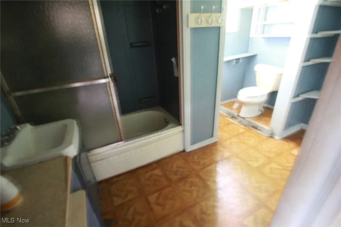 Full bathroom featuring toilet and combined bath / shower with glass door