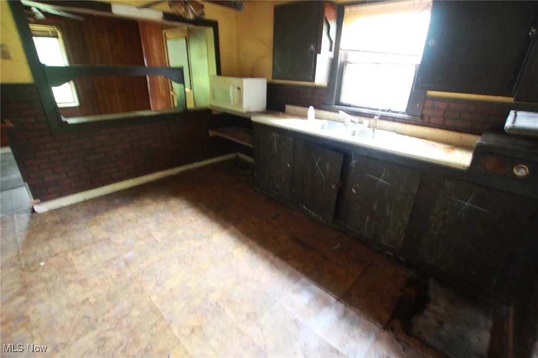 Kitchen with healthy amount of natural light, white microwave, and ceiling fan