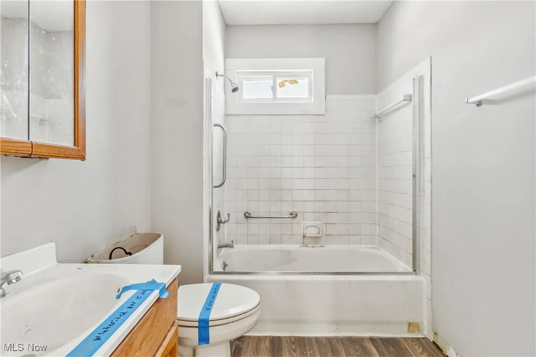 Bathroom featuring toilet, shower / bathing tub combination, wood finished floors, and vanity