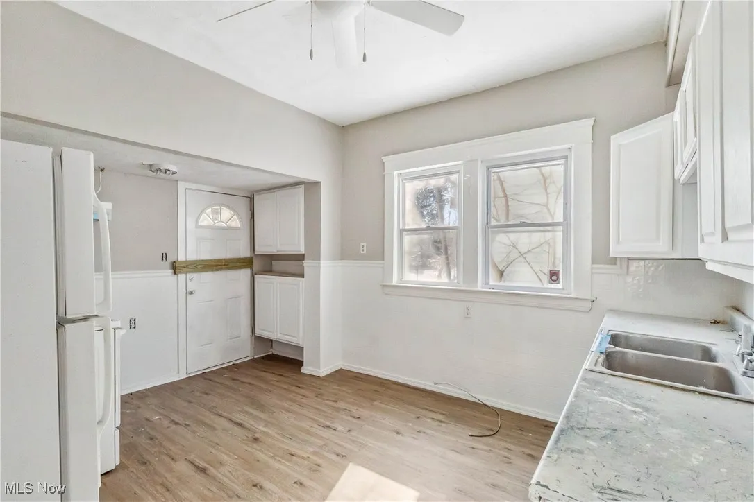 Kitchen featuring a sink, white cabinetry, light countertops, light wood-type flooring, and freestanding refrigerator