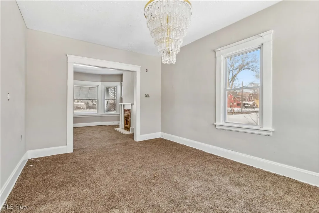 Unfurnished dining area featuring plenty of natural light, carpet, baseboards, and a notable chandelier