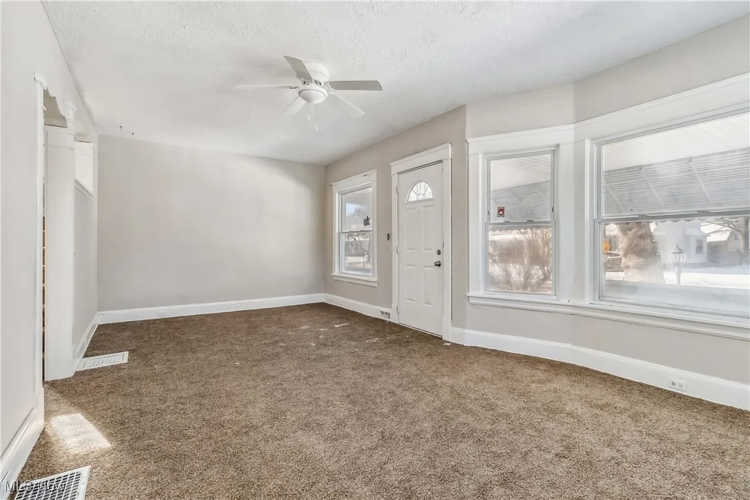 Entrance foyer featuring baseboards, visible vents, dark carpet, and a textured ceiling