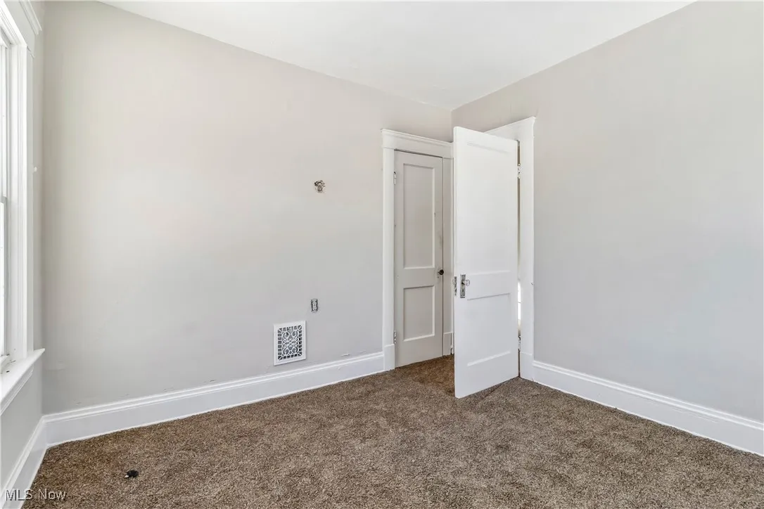 Carpeted spare room with visible vents and baseboards