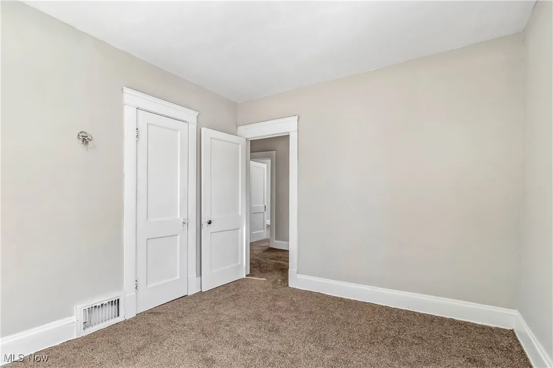 Spare room with carpet, visible vents, and baseboards