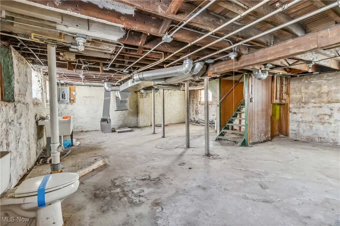 Unfinished basement with electric panel and stairs