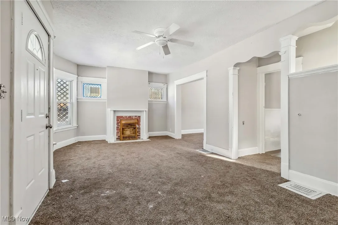 Unfurnished living room with carpet floors, a brick fireplace, baseboards, and a textured ceiling