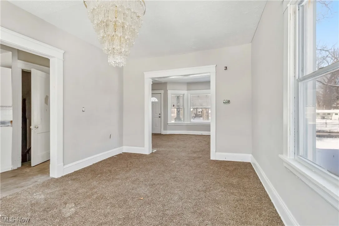 Unfurnished dining area with a chandelier, carpet, and baseboards