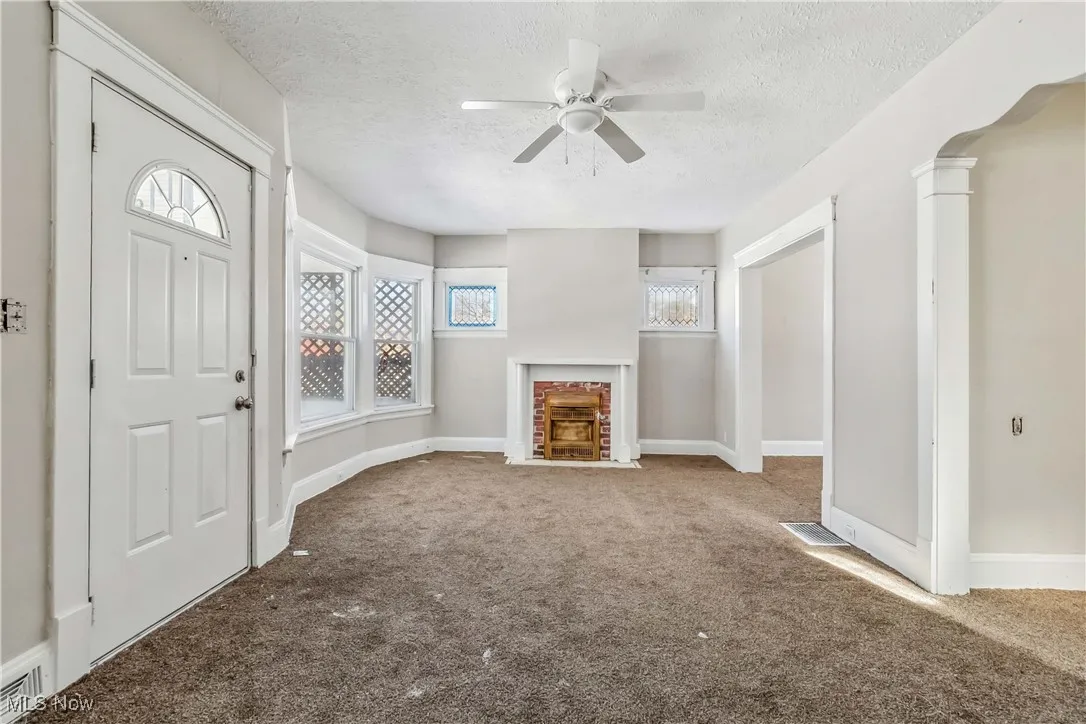 Unfurnished living room featuring carpet, baseboards, a textured ceiling, and a fireplace with flush hearth