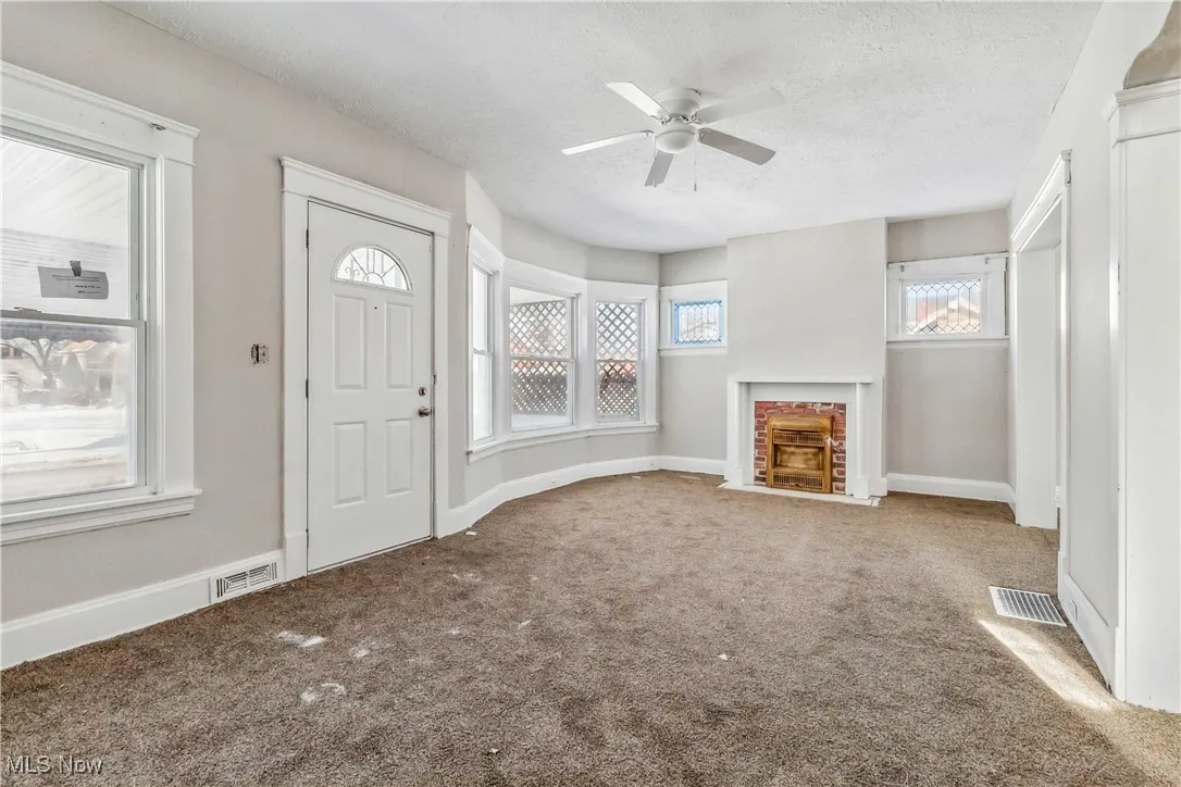Entrance foyer with carpet, a textured ceiling, a wealth of natural light, and a fireplace with flush hearth