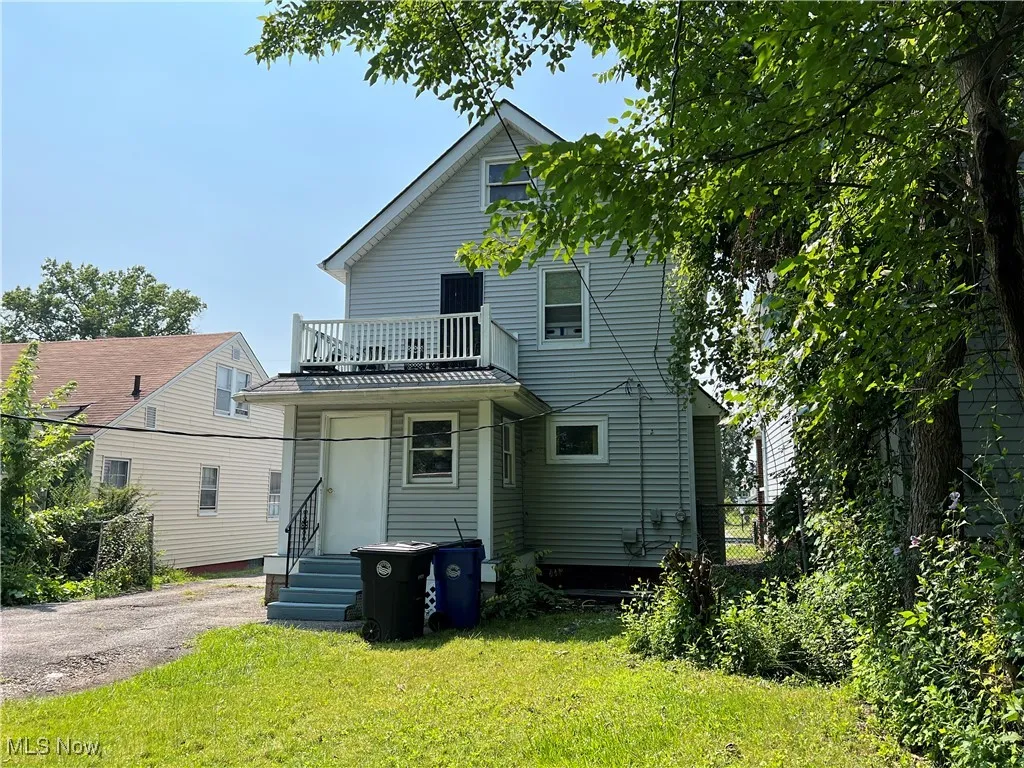 Rear view of property with a balcony and a lawn