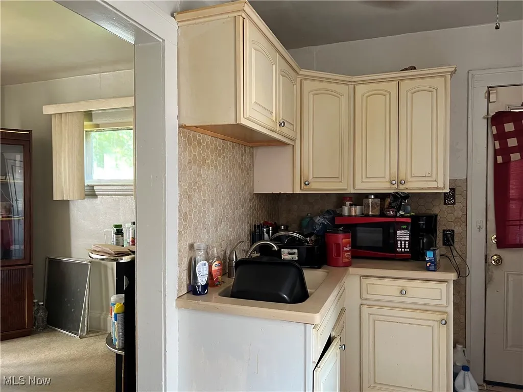 Kitchen featuring cream cabinetry, light countertops, and backsplash