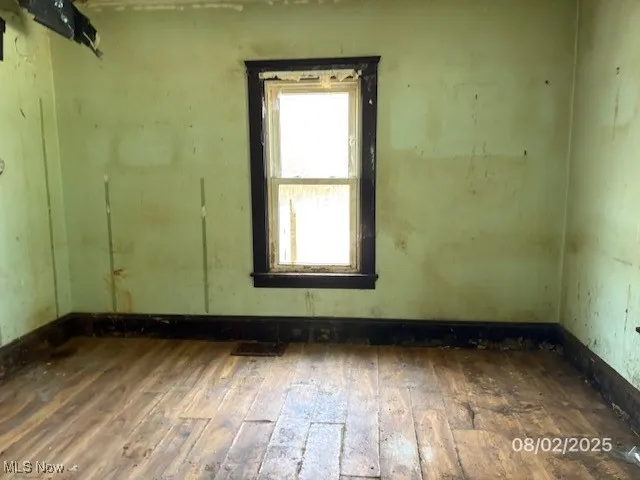 Unfurnished room featuring hardwood / wood-style flooring and baseboards