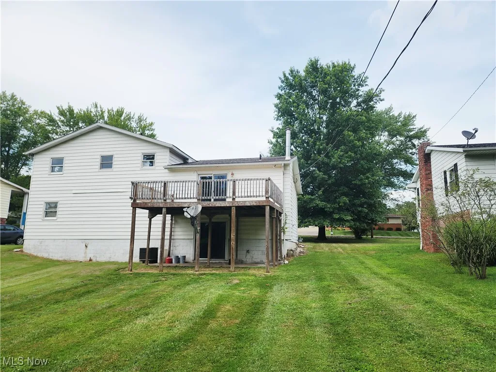 Rear view of property featuring a wooden deck and a yard