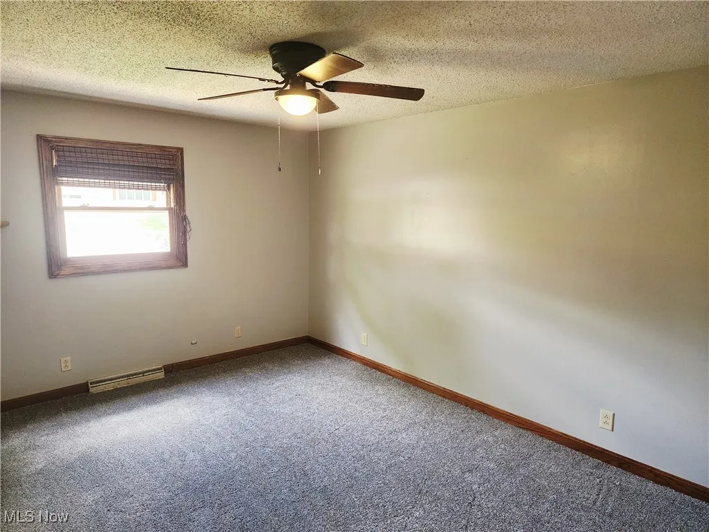 Carpeted spare room with a textured ceiling and ceiling fan